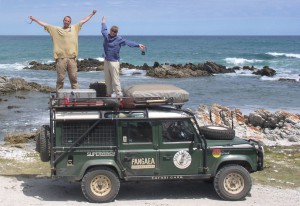 Jen and Witt standing on their Land Rover at the southern tip of Africa